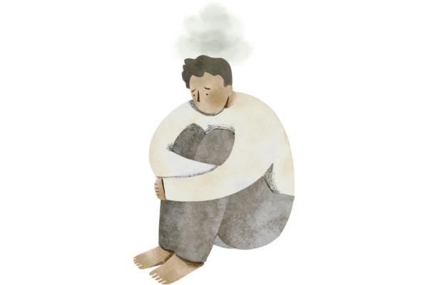 A person sitting curled up, hugging their feet, looking sad and withdrawn.